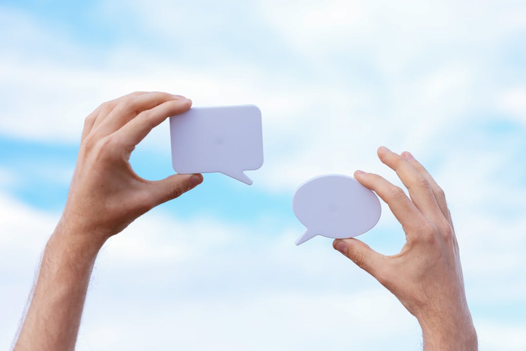 "Ha sido un antes y un después" Close-up of hands holding speech bubbles, symbolizing communication and dialogue against a blue sky.
