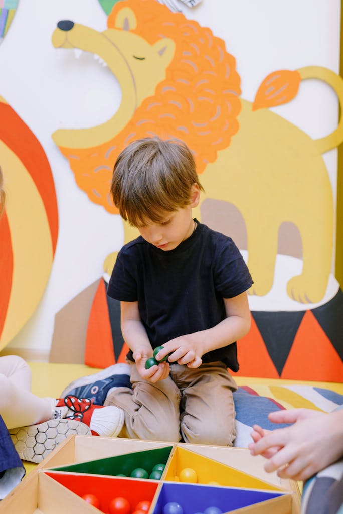 Terapia Infantil Especializada Cute young boy playing with colorful balls indoors, surrounded by playful decor.
